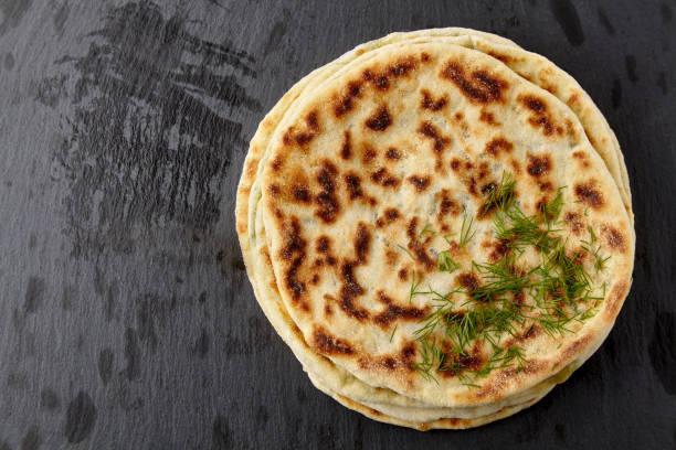 istock Flatbread with cheese and herbs on a dark stone table 1402506652