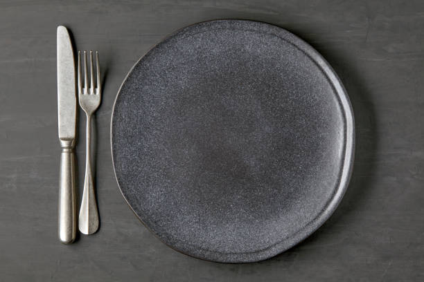 istock Dark plate on a dark concrete background with cutlery 1402512716