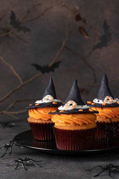 istock Halloween cupcakes decorated witch hat from mastic on brown background with spiders and bats, sweets for kids on Halloween party 1402513962