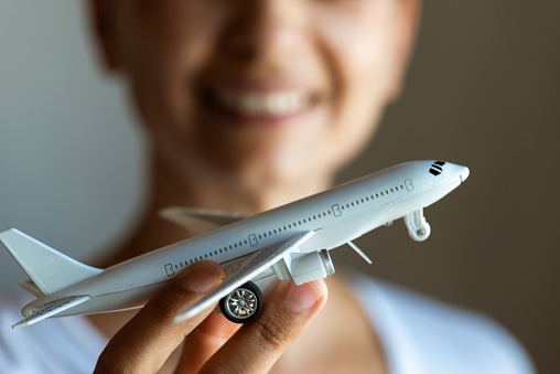 Unrecognizable female with a toothy smile is showing a model plane to camera.