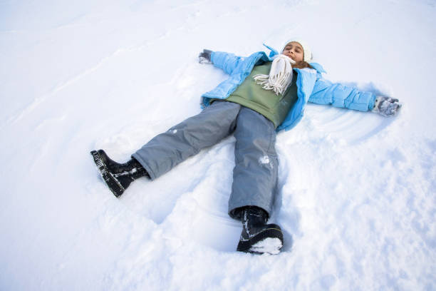 istock Pretty girl making angel on snow. 1402515538