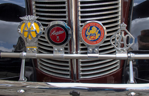 Hadleigh, Suffolk, UK - June 2022: A collection of old motor badges on the front of a vintage car in Suffolk, UK