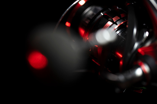 close-up shoot of spinning fishing reel on black background