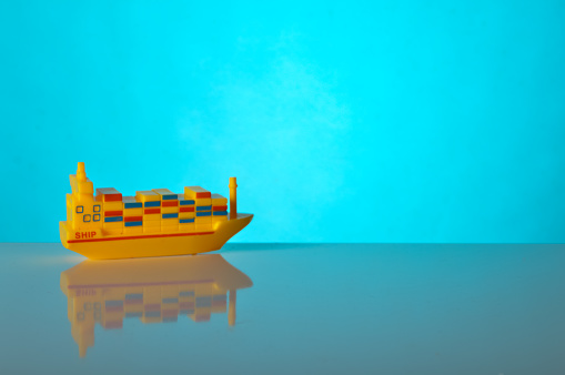 Toy cargo ship sailing isolated on a blue background. Copy space for the text.