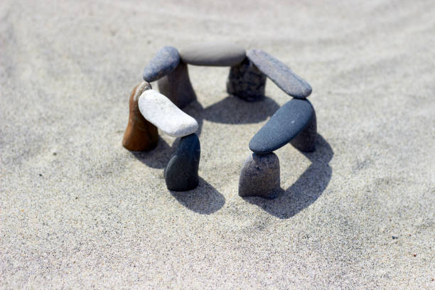 Balanced pebbles on the sandy coast. Stones are stacked on the beach. Little stonehenge