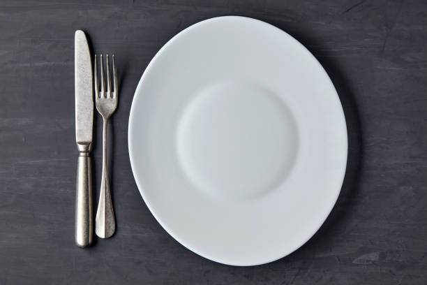 istock Oval white plate on a dark concrete background with cutlery 1402520338