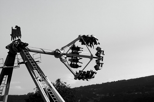 Lugo, Spain- October 10, 2021: Fun fair in Lugo city, Spain, during annual San Froilán traditional celebrations . Amusement park ride, people having fun. Black and white view
