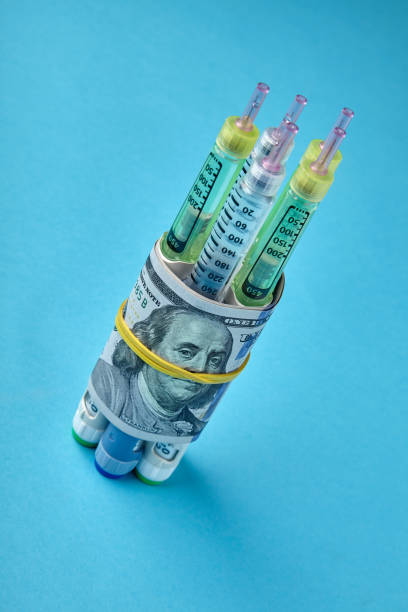 istock Insulin syringe pens wrapped in dollar bills on a blue background 1402522802