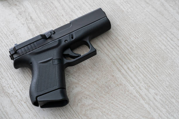 istock Modern self loading pistol isolated on wooden background. Semi automatic gun with belt clip 1402523909