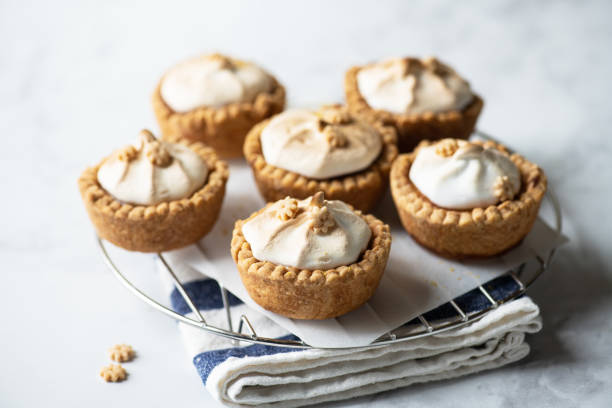 istock Lemon curd tartlets with whipped meringue on a wire rack on a gray background. 1402524605