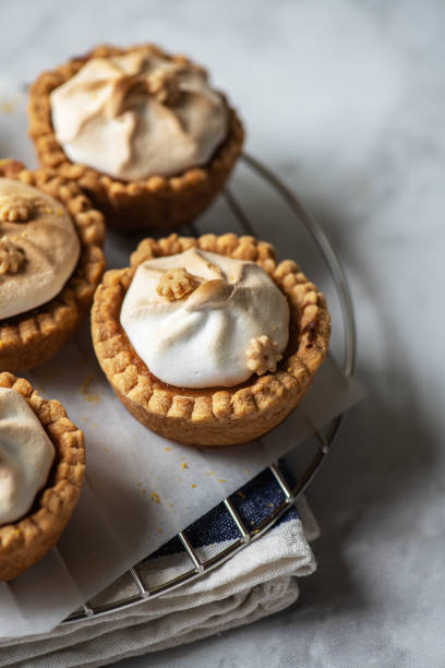 istock Lemon curd tartlets with whipped meringue on a wire rack. Close up. 1402524609
