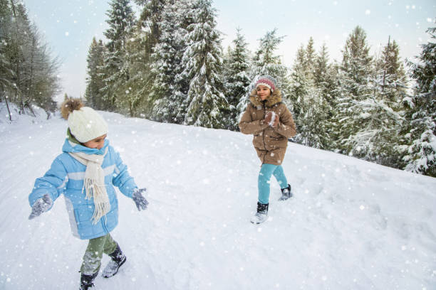 istock Playful kids throwing snowballs in forest. 1402527764