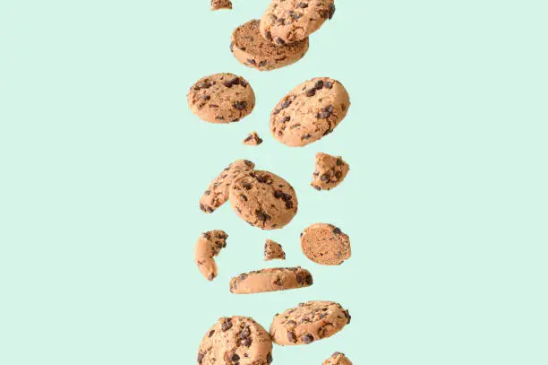 Chocolate chip cookie on a green background aesthetic food concept flying chocolate biscuits