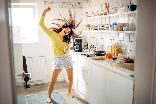 Funny young woman dancing in modern kitchen