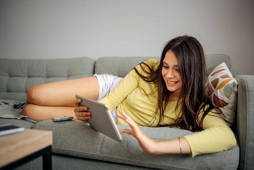 Young woman using a digital tablet on the sofa at home