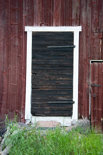 A rather worn and weather-beaten door, with old fashion iron hinges.