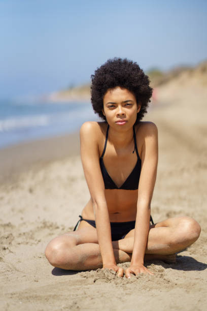 istock Black woman in bikini on sandy seashore 1402541077