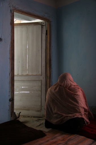 An afghan widow sitting near the door to her tea-room.