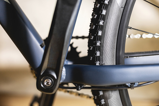 Part of a blue bicycle frame with off-road tires on the rear wheel, with one star on the cranks and a chain, close-up