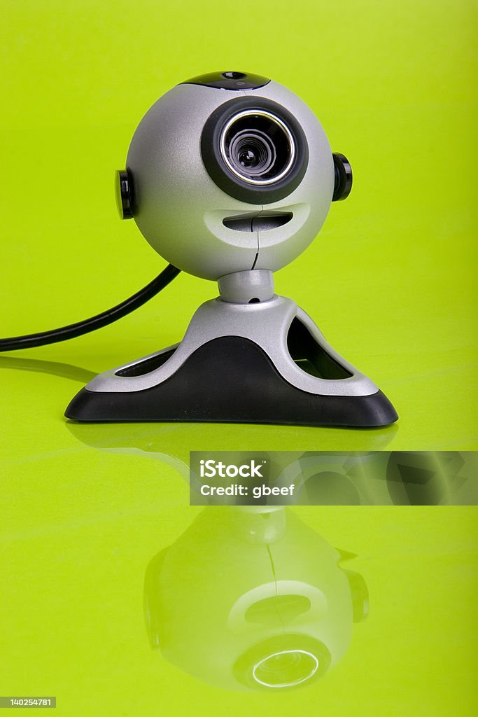 webcam on a green ground webcam on a green background, sitting on top of a reflective surface. Camera - Photographic Equipment Stock Photo