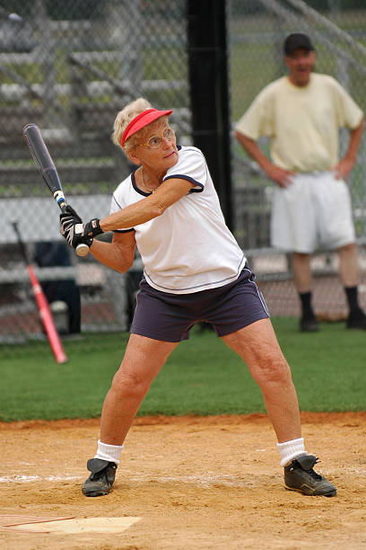 Senior woman up to bat. Older woman at bat in senior softball game. old baseball stock pictures, royalty-free photos & images