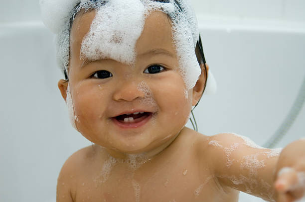 smiling baby taking a foam bath stock photo