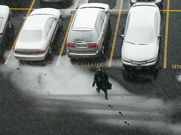 Businessman walking to his car in a snowy parking lot.