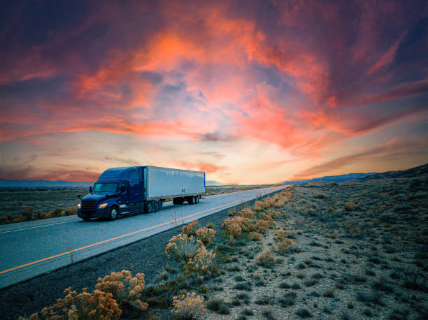 low-angle-luft-drohnenaufnahme eines sattelschleppers auf der autobahn mit einem farbenfrohen sonnenuntergang - truck space desert utah stock-fotos und bilder