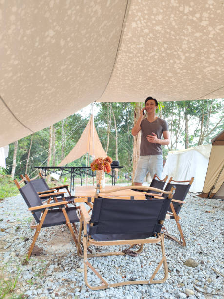 istock Young Asian man working with smartphone during his camping vacation in forest 1402563746