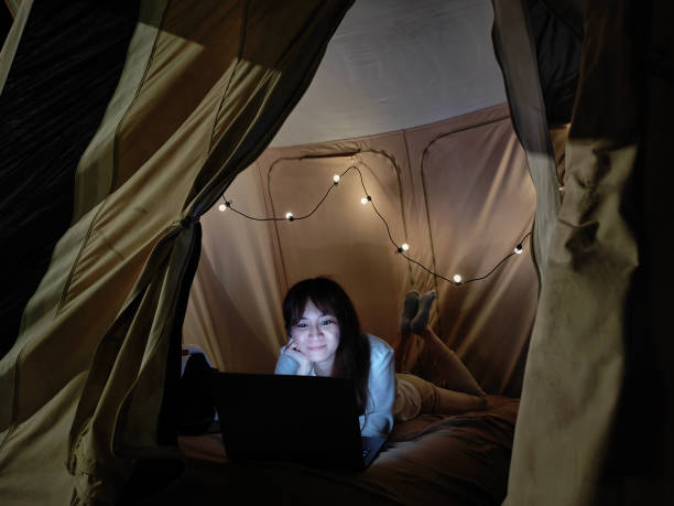 istock Young Asian woman in tent using laptop at night 1402563790