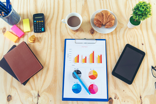 Office laptop business financial document chart and graph on wooden table with coffee cup. Flat lay notebook computer laptop on office desk. No people business graph chart mockup on business workspace