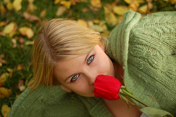 Beautiful young woman smelling a rose. stock photo