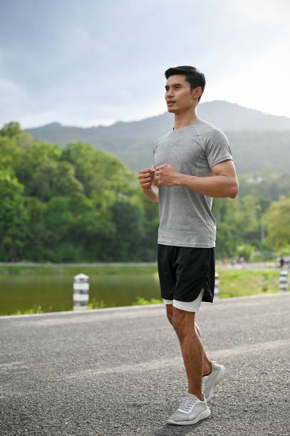istock Handsome and active asian man jogging or running in the beautiful green park. 1402567097