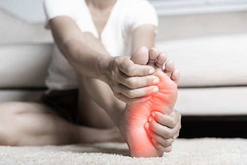 Mujer asiática sintiendo dolor en el pie en casa photo