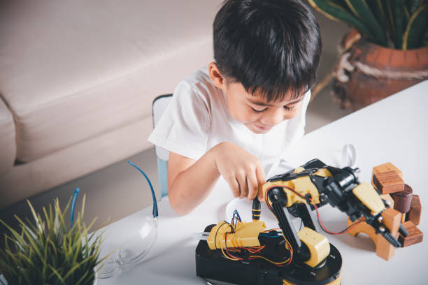 istock Happy Asian little kid boy using screwdriver to fixes screws robotic machine arm in home workshop 1402571539