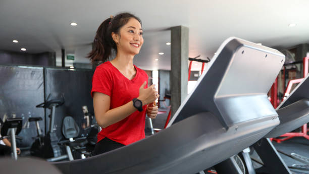 Asian young woman is having jogging on the treadmill stock photo