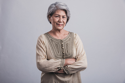 Closeup portrait smiling confident senior woman sitting on comfortable sofa at home. Happy retired female with stylish gray hair, white teeth looking away. Natural beauty, healthy lifestyle concept