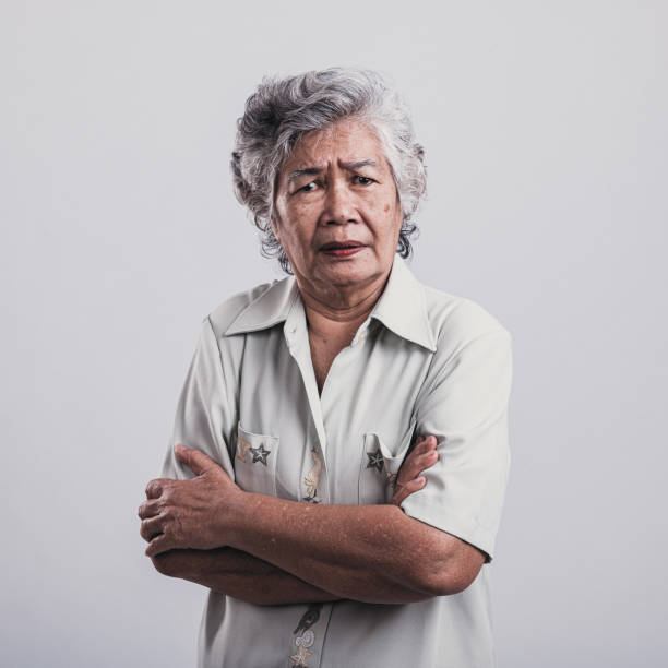 сердитый портрет старшей женщины на сером фоне. - distraught 70s asian ethnicity women стоковые фото и изображения