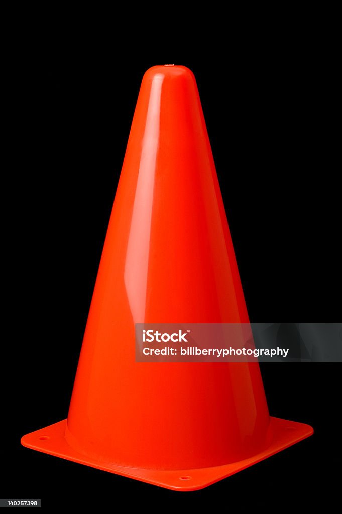 Pylon Upright Orange pylon standing upright isolated on a black background Cone Shape Stock Photo