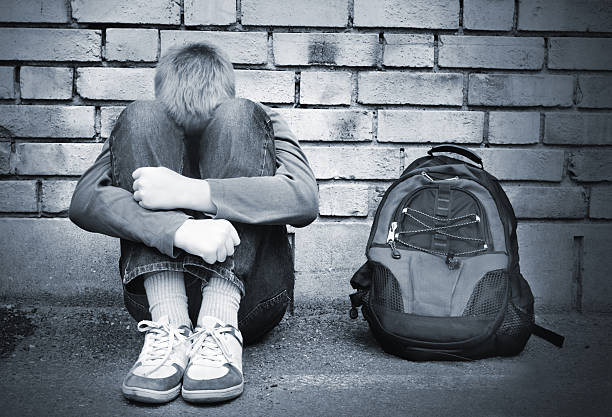 istock School boy sitting against brick wall being upset 140257430