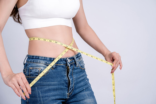 Woman in jeans with tape measure show thin body.Diet and weight control. Weight loss and slimming concept.