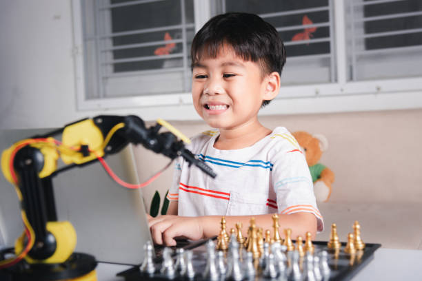 istock Asian little boy programming code to robot machine arm on laptop for play chess 1402577884
