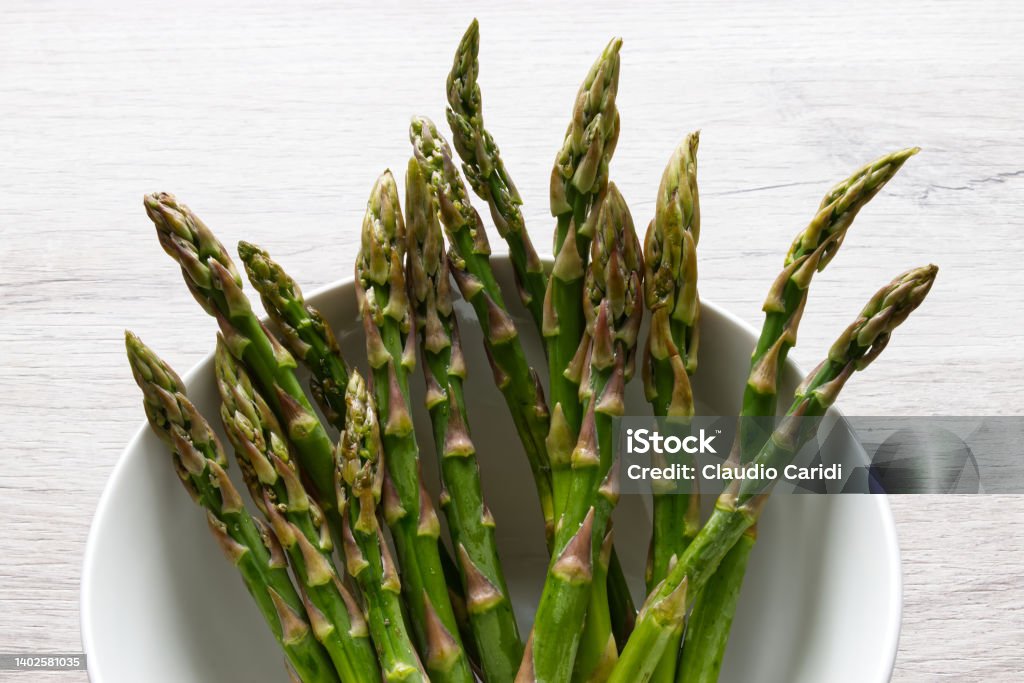 Fresh asparagus in a bowl isolated on wooden background Asparagus Stock Photo