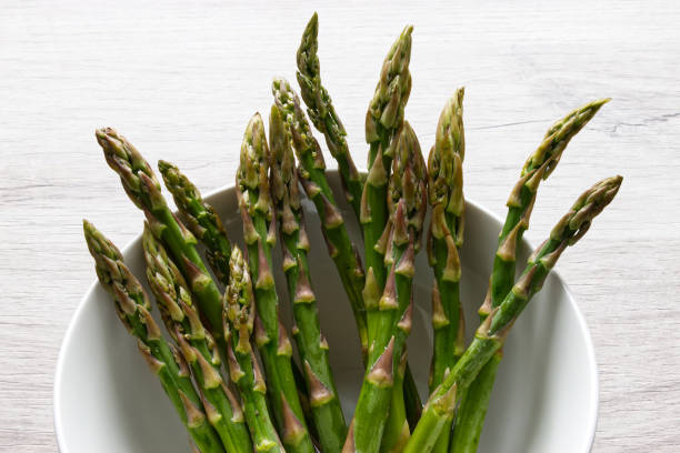Fresh asparagus in a bowl isolated on wooden background stock photo