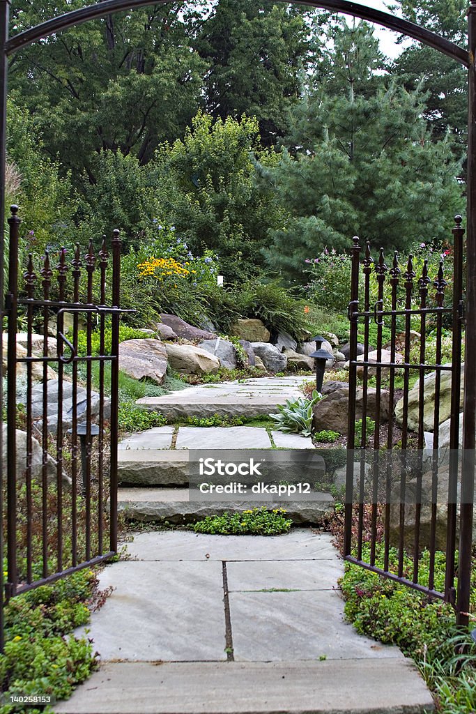 Garden Gate The  black wrought-iron garden gate entrance to an enchanted, peaceful flower garden. Gate Stock Photo