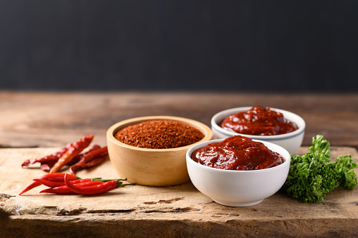 Korean gochujang (red chili paste) in bowl on wooden table, spicy and sweet fermented condiment in Korean food