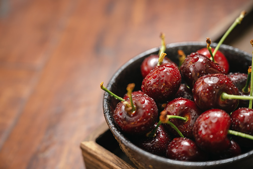 heap of fresh garden cherries in the bowl isolated on pastel background, close-up