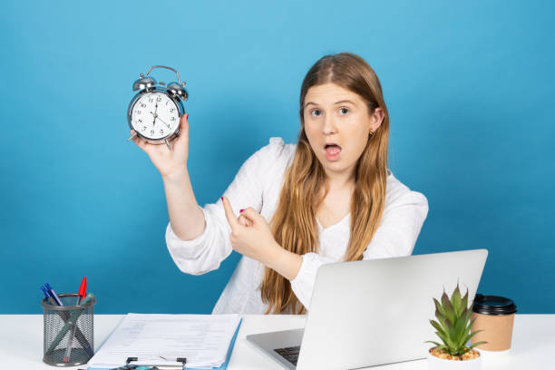 istock Pretty office worker pointing at alarm clock 1402590619