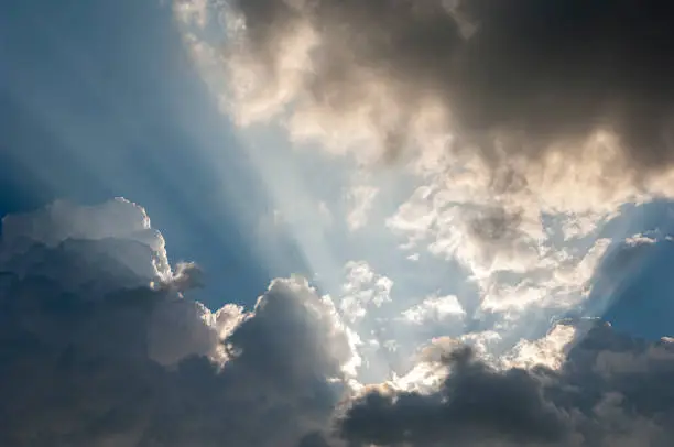 Sunbeams of the obscured sun make their way through the cloud cover