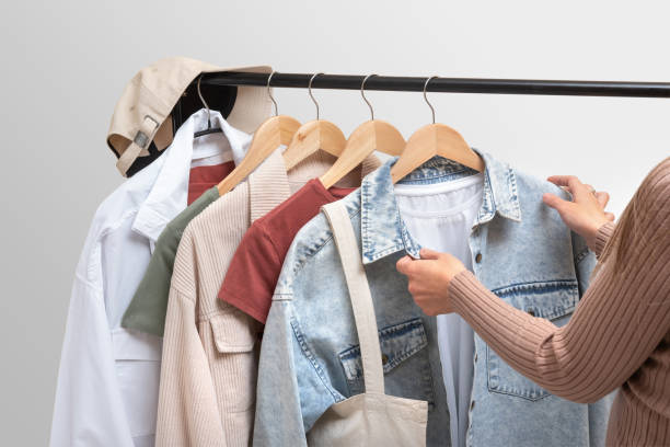 istock Fashion stylist chooses clothes on railing in showroom. Basic women`s clothes and eco bag on white background. Woman collection of clothes on a rack. Spring and summer fashion trending concept. Railing with stylish female clothes, clothing retails concept 1402594708